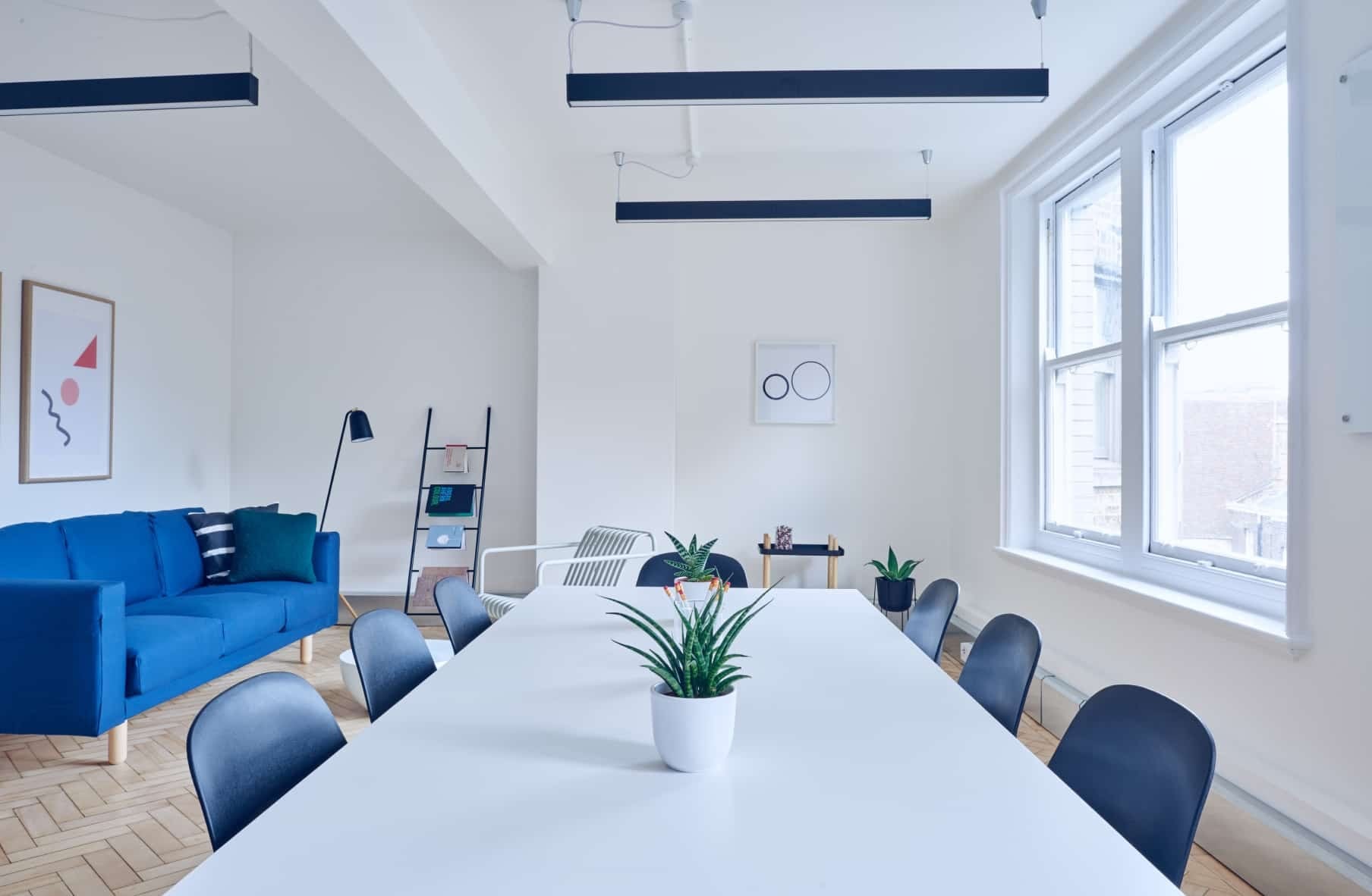 Sala riunioni luminosa con divano blu e tavolo bianco